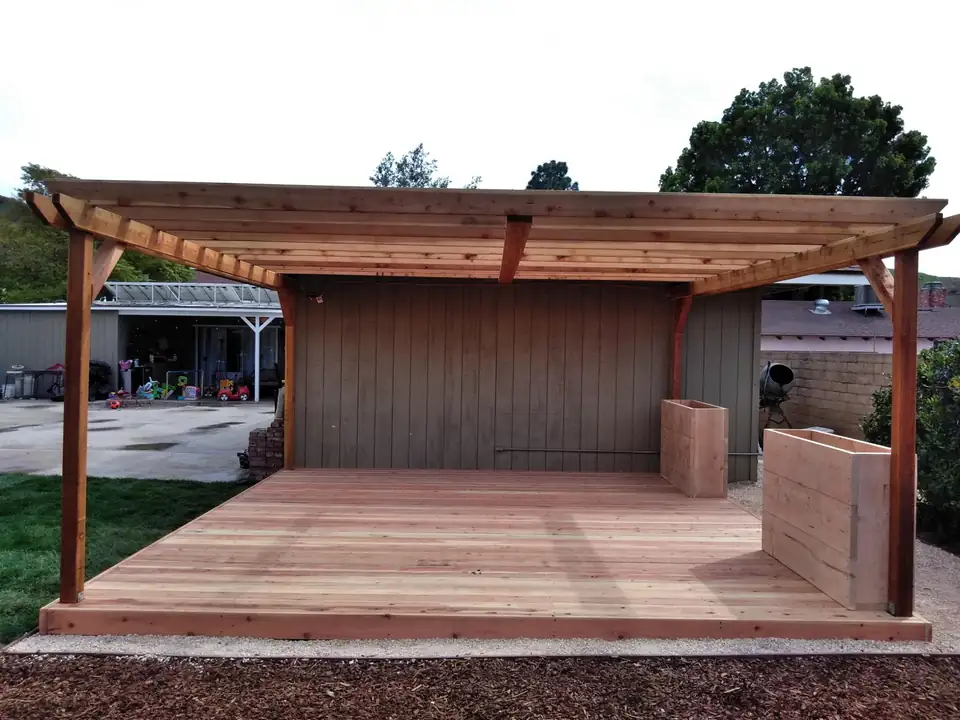 A finished back yard build — redwood pergola over a deck, planting, and lawn